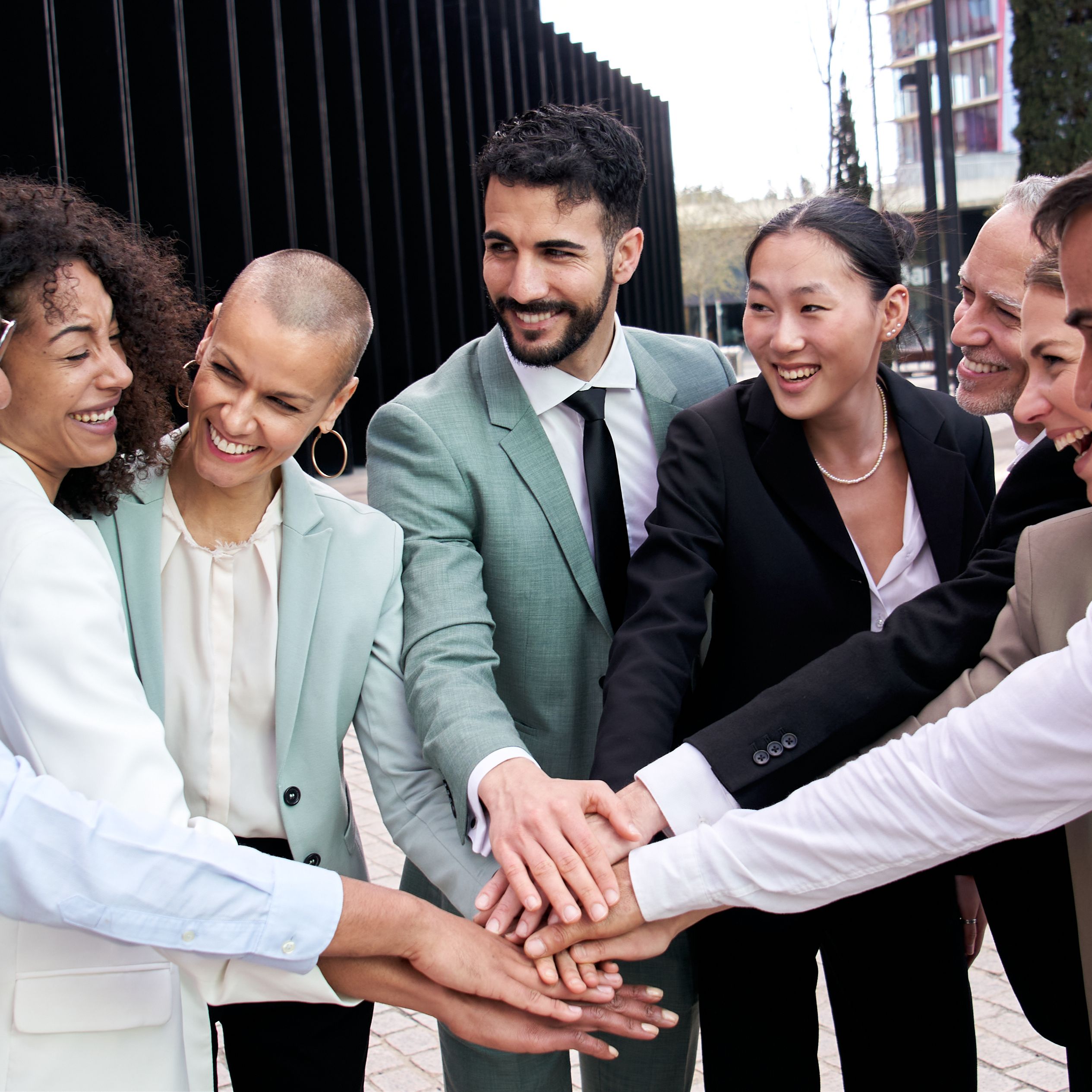 People in suits putting hands together in a huddle